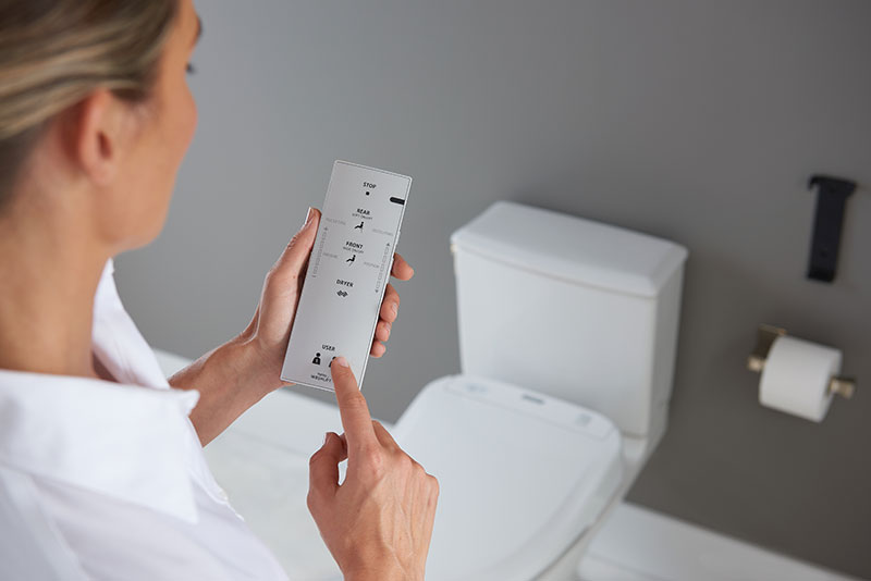 A person operating a TOTO WASHLET bidet seat remote chooses the user setting tailored to their preferences.